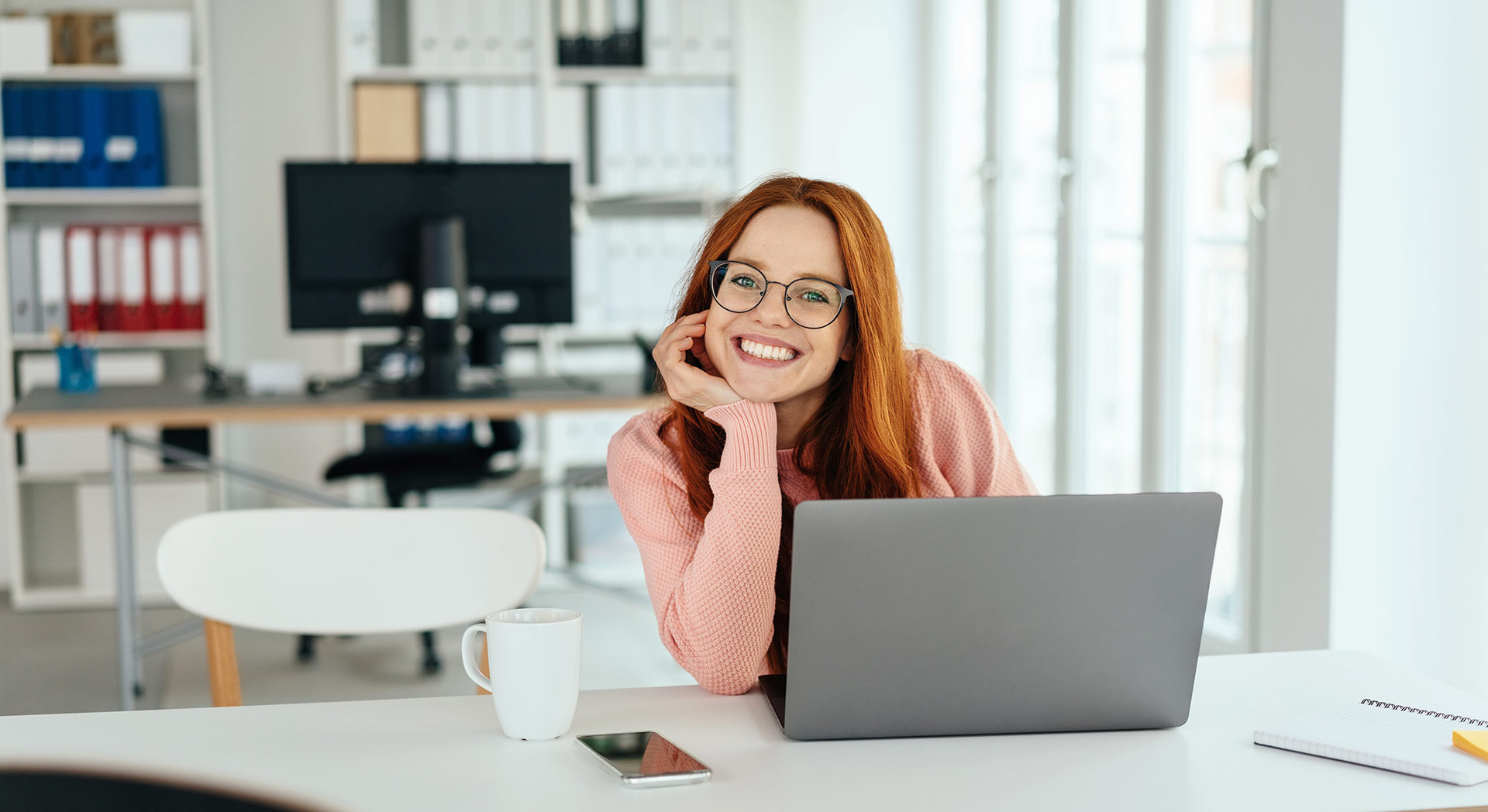Junge Frau am Schreibtisch vor einem Laptop